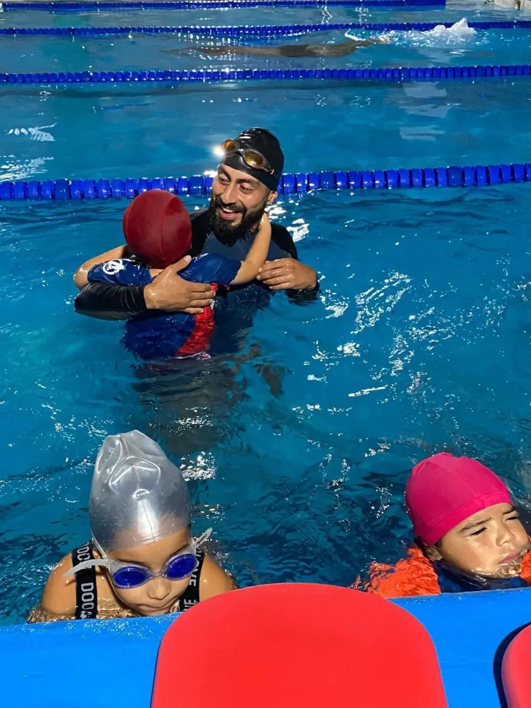 Hombre abrazando a niño en piscina clases de natacion